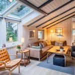 Wohnzimmer mit Sofa, Sitzgelegenheiten und Fenstern zum Garten.
