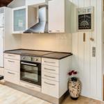 Küche mit Dunstabzug, Kühlschrank und Ofen. Flur mit Holzboden und Tür.
