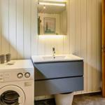 Badezimmer mit Waschmaschine, Spiegel und Holztür.