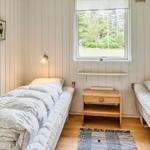 Zwei Betten mit weißen Bettwäsche, Holzkommode und Fenster mit Blick auf Grünflächen.