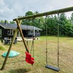 Schwarzes Haus mit Spielplatz und Garten. Roter Sitzschwinger und Holzschaukel.