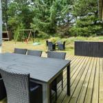 Terrasse mit Tisch und Stühlen, Blick auf Grasfläche und Spielplatz.