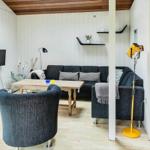 Wohnbereich mit Sofa, Tisch und Fernseher. Küche mit Arbeitsplatte und Kühlschrank.