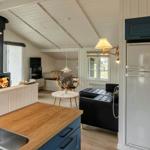 Küche mit Holzplatte und Kühlschrank. Wohnbereich mit Sofa, Kamin und TV.