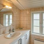 Badezimmer mit Waschbecken, Spiegel und Fenster