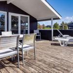 Terrasse mit Tisch, Stühlen und Liegen. Dunkle Holzwände und weißer Balkon.