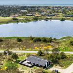 Ein Haus am See mit Blick auf die Küste und grüne Landschaft.
