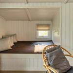 Schlafzimmer mit Bett, Stuhl und Fenster. Wandverkleidung und TV sichtbar.