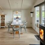 Essbereich mit Holztisch, Stühlen und Kaminofen. Blick auf Terrasse mit Garten.