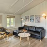 Wohnzimmer mit Sofa, Stuhl und Küchenbereich. Holzdielen und weiße Wände.