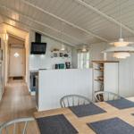 Küche und Essbereich mit Tisch, Stühlen und Fenster. Wohnbereich mit Sofa und Wandbehang.