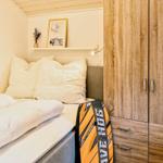 Schlafzimmer mit Bett, Kleiderschrank und Wandregal mit Bild und Pflanze.