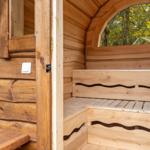 Holzsauna mit Sitzbänken und Bogenfenster im Wald