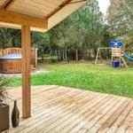 Holzterrasse mit Blick auf Garten, Spielplatz und Whirlpool.