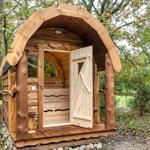 Holzsauna im Wald mit offener Tür und Sitzbänken