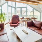Wohnraum mit braunen Ledermöbeln, großem Fenster und Holzdecke.