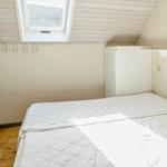 Schlafzimmer mit Dachschrägen, Dachfenster und weißem Bett.