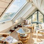 Dachgeschosszimmer mit Holzwand, Sitzgelegenheiten und großem Fensterblick.
