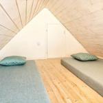 Zwei Schlafplätze in einem Dachbodenzimmer mit Holzwand und Boden.
