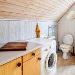 Wohnraum mit Waschmaschine, Spüle und Toilette. Holzdecke und -boden.