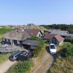 Haus mit Strohdach, Terrasse und Parkplatz auf grüner Anhöhe