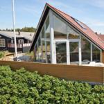 Moderne Holzhütte mit großem Glasbereich und Terrasse umgeben von Grünflächen.