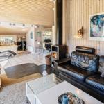 Wohnzimmer mit Ledersofa, Kamin und TV. Holzwände und Blick in Schlafzimmer.
