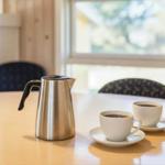 Auf dem Tisch stehen zwei Tassen Kaffee und eine Thermokanne.