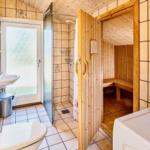 Badezimmer mit Dusche, Toilette, Waschbecken und Sauna.