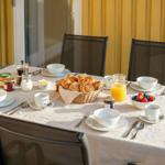 Tisch mit Frühstück auf Terrasse, Körbchen mit Croissants, Obst und Getränke.