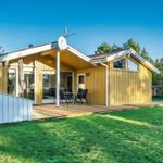 Ein gelbes Haus mit Terrasse und Garten. Es hat eine Satellitenschüssel und große Fenster.