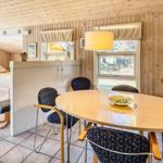 Esszimmer mit runden Tisch und Stühlen, Holzwände, Fenster und Blumen.
