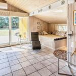 Wohnraum mit Schlafbereich, Holzwand und Terrassentür. Fliesenboden und Sitzmöbel.