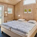 Schlafzimmer mit Holzwand, Bett, Nachttisch und Tür zum Garten.