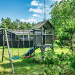Schwarzes Ferienhaus mit Spielplatz im Grün.