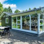 Moderne Ferienhaus mit großem Glasbereich und Terrasse mit Tisch und Stühlen.
