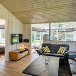 Wohnzimmer mit Ledersofa, Holzwand und TV. Durchgang zur Schlafzimmer.