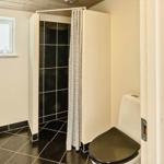 Badezimmer mit Dusche, Toilette und Fenster mit Flaschen auf Sims.