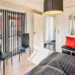 Schlafzimmer mit Bett, Sitzbank, zwei Stühlen und Blick auf Balkon.