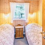 Zwei Betten mit gemusterten Bettdecken stehen in einem Raum mit Holzwänden und einem Fenster.