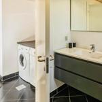 Badezimmer mit Waschmaschine und Spiegelschrank. Türklinken und Handtuch an der Wand.