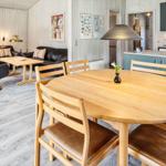 Essbereich mit Holztisch und Stühlen. Küche und Wohnzimmer im Hintergrund.
