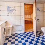 Badezimmer mit Sauna, Toilette, Waschmaschine und blau-weißem Bodenfliesenmuster.