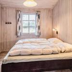 Schlafzimmer mit Holzwand, Bett, Fenster und Wandlampen.