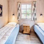 Zwei Einzelbetten, ein Fenster, Holzwand und Nachttisch