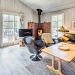 Wohnzimmer mit Holzfußboden, Sofa, Stühlen und Kaminofen.