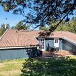 Ein Haus mit Terrasse, Tisch und Stühlen, umgeben von Bäumen und Gras.