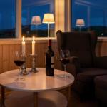 Runde Tisch mit Weinglas, Flasche und Kerzen vor Fenster mit Blick nach draußen.