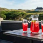 Auf der Terrasse steht ein Tisch mit zwei Gläsern und einer Karaffe mit rotem Getränk.