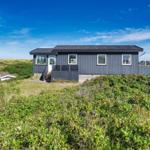 Moderne Strandhaus mit Blick auf Dünen und klarem Himmel.
